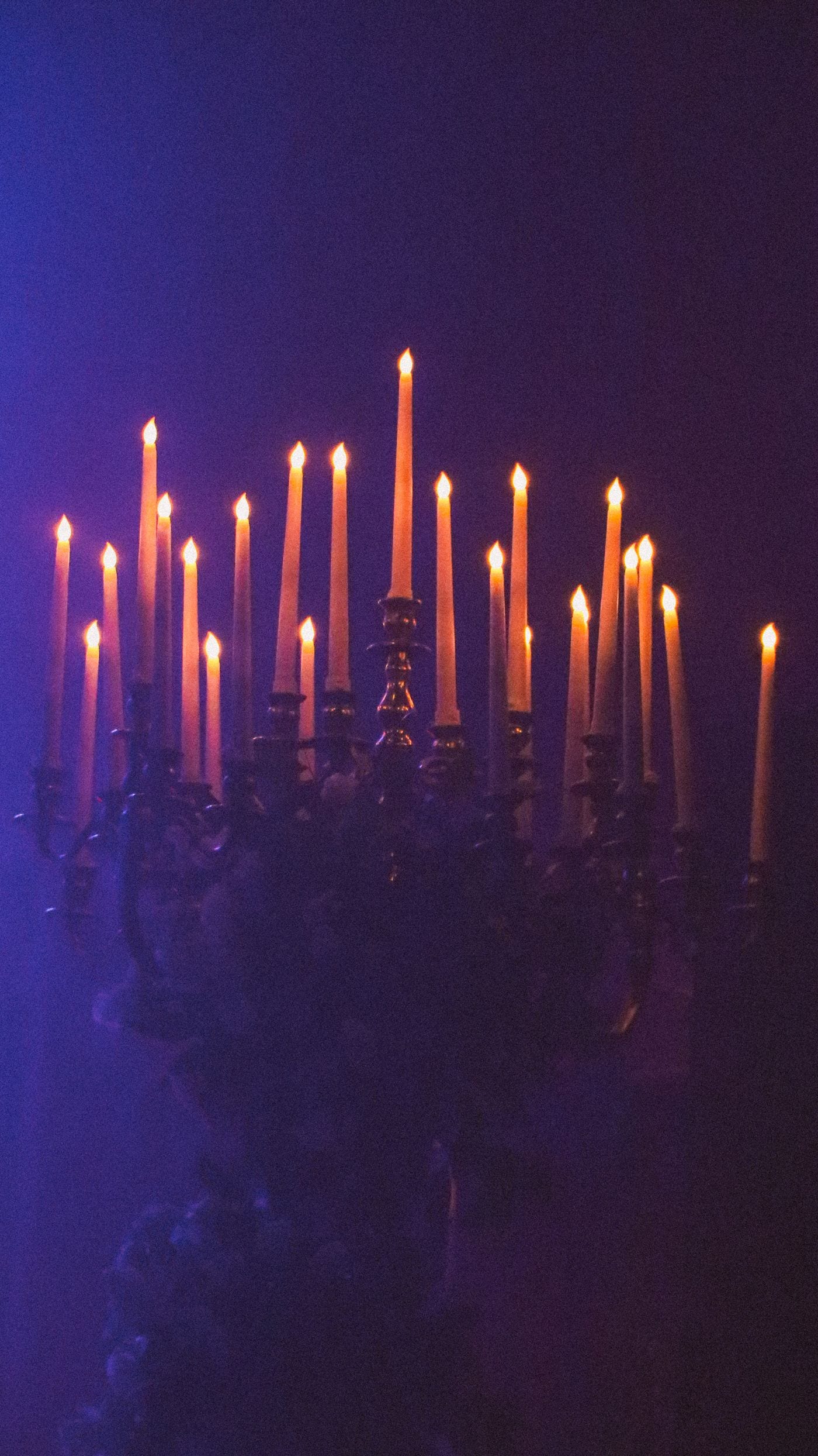 Tall candelabra of lit tapers glowing against a deep blue haze