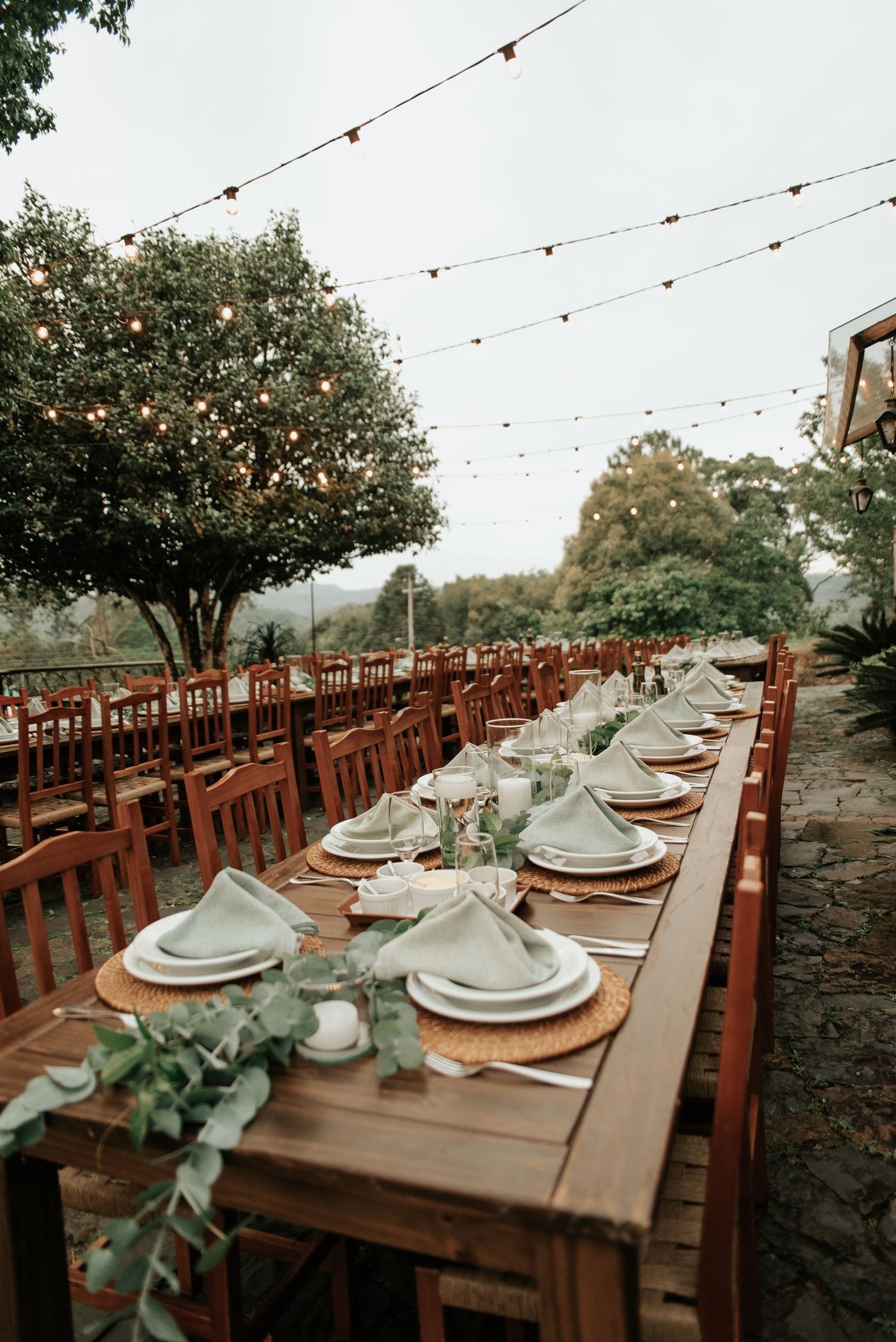 Summer garden banquet set with candles beneath criss-crossing string lights
