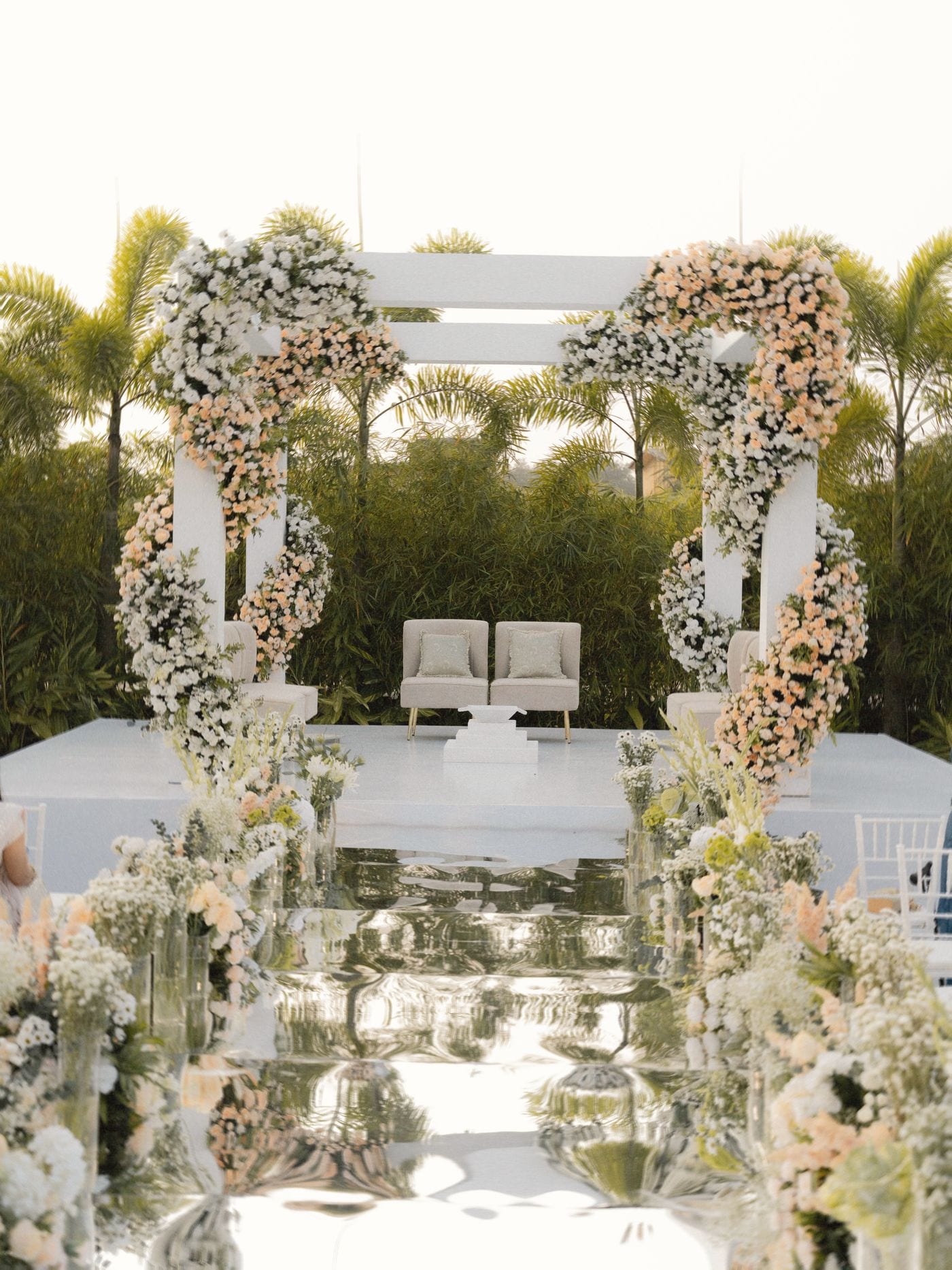 White floral canopy with peach roses above a mirrored aisle